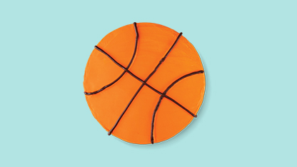 This is a graphic design featuring an orange basketball court overlaid on the surface of what appears to be a blue floor, giving an optical illusion that the court is floating above it. The perspective is slightly tilted, making the scene look like a real-life setup rather than an image manipulation.